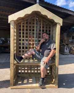 A photo of Sussex Timber Products Ltd founder, Gary, sitting in a wooden shelter