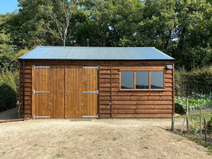 A photo of a timber building with 2 large barn doors and a window on the right